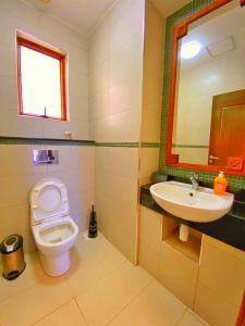 un bagno con un water, un lavandino e uno specchio di Shanzu Oceanline Luxury Suites, Royal Sharza a Mombasa