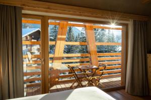 a bedroom with a view of a balcony with a table at Au Charmant Petit Lac - Ecohotel Parc & Spa in Champoluc