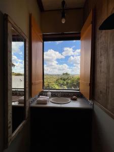 La salle de bains est pourvue d'une fenêtre avec un lavabo et une vue. dans l'établissement Cores da Mata - Casa de Charme, à Tiradentes