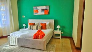 una camera da letto con pareti verdi e un letto con cuscini arancioni di Shanzu Oceanline Luxury Suites, Royal Sharza a Mombasa Altre 19 foto