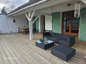 a patio with a couch and a table on a deck at Chez yoan et laurie in Corbelin