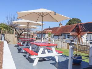 a row of picnic tables with an umbrella at Flat 4, Big Tree Holiday Flats in Paignton