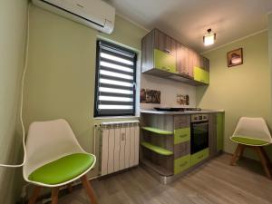 a kitchen with green cabinets and two chairs at SouthBrise Apartments - Garsoniera Mangalia - 100m de plajă in Mangalia