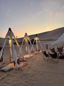 a group of chairs and umbrellas on a beach at Duna Camp Huacachina in Ica