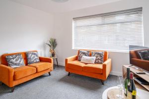 two orange chairs in a living room with a window at Skipton Lodge in Billingham