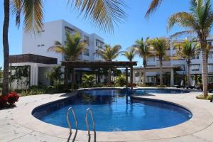 a pool in front of a building with palm trees at apartment 5 minutes from the beach in Mazatlán