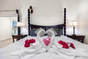 uma cama com toalhas brancas e flores vermelhas em Palma Real 29 em Palm Beach