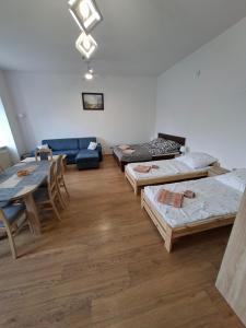 a room with several beds and a table and a couch at Apartament Wolności in Szczytna