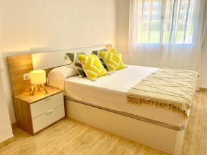 a bedroom with a bed with yellow pillows and a window at Frente al mar con piscina para 4 in L'Ampolla