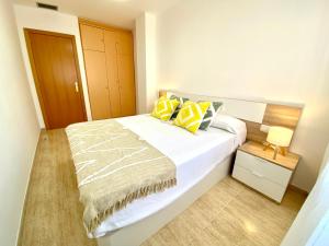 a bedroom with a large white bed with yellow pillows at Frente al mar con piscina para 4 in L'Ampolla