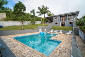 a swimming pool with chairs and a house at Bonatto's House in Cotia