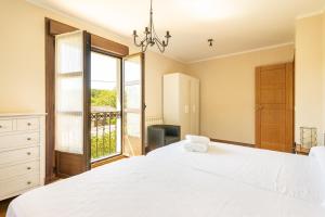 ein Schlafzimmer mit einem großen weißen Bett und einem Fenster in der Unterkunft La Corvera en Collera, Ribadesella in Collera