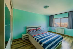 a bedroom with blue walls and a bed with two pillows at M Suite - close to the beach in Mangalia