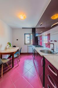 a kitchen with a table and a pink floor at M Apartment aproape de plaja in Mangalia
