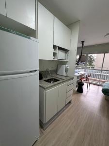 eine weiße Küche mit Spüle und Kühlschrank in der Unterkunft Nari Loft in São Paulo