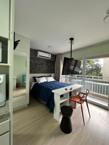 a bedroom with a bed and a desk and a television at Nari Loft in São Paulo