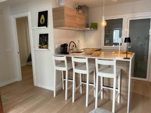 a kitchen with a counter with stools at a kitchen island at Olive Home in Santiago de Compostela