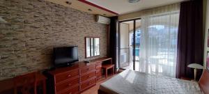 a bedroom with a television and a brick wall at GL Beach Resort Private Studio Sozopol in Sozopol