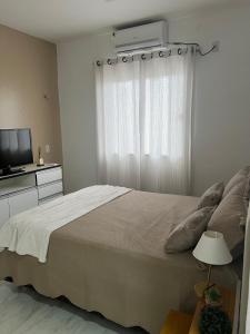 una camera con un letto e una finestra con condizionatore d'aria di Suite pequena em casa de familia 15km de Belém ad Ananindeua