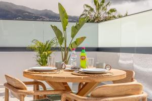 ein Holztisch mit Tellern und Getränken auf einem Balkon in der Unterkunft Casa da Ilha in Funchal