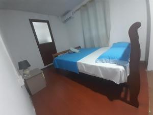a bedroom with a bed with blue sheets and a mirror at La Belle du Sud in Rodrigues Island