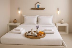 a white bed with a tray of food on it at Virginia Studios in Tinos