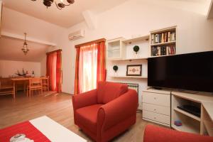 ein Wohnzimmer mit einem roten Stuhl und einem Flachbild-TV in der Unterkunft Apartment Macan in Cavtat