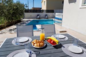 einen Tisch mit einem Teller Essen und einer Flasche Orangensaft in der Unterkunft Villa Trapezium - private heated pool & table soccer in Kaštela
