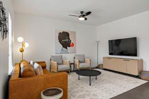 a living room with a couch and a flat screen tv at South Lamar Stay - Pickleball, Sauna & Cold Plunge in Austin