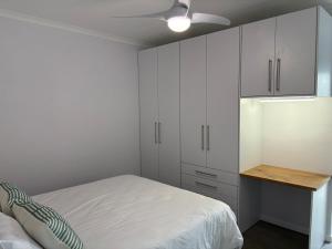 ein weißes Schlafzimmer mit einem Bett und einem Schreibtisch in der Unterkunft Comfy Cottage in Walvis Bay