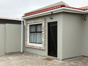 ein kleines Haus mit einem Fenster und einer Tür in der Unterkunft Comfy Cottage in Walvis Bay