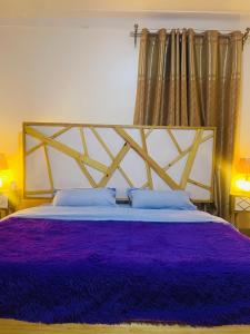 a bedroom with a large bed with purple sheets at JK Cozy Home in Kampala