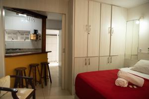 a bedroom with a red bed and a kitchen at Bouganville Suites in Angra dos Reis