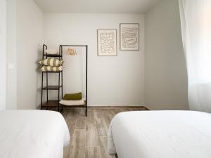 a white bedroom with two beds and a chair at ChillaHomes 103 in Candeleda