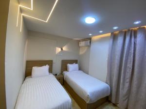 two beds in a small room with white sheets at Isis Pyramids View Inn in Cairo