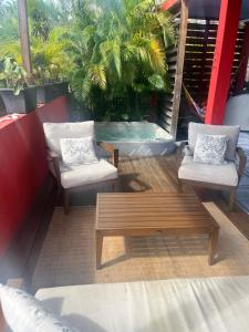a patio with two chairs and a wooden bench at Villa Victoria in Bouillante