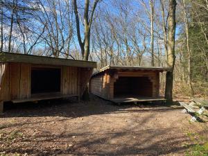 two large wooden buildings in a forest with trees at Krogager Primitiv Camping - Krogen in Grindsted +3 photos
