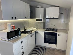 a white kitchen with white cabinets and a microwave at Happy apartment 2 in Chiajna +6 photos