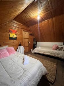 a bedroom with two beds in a wooden cabin at La cabaña de la abuela in Sutatausa