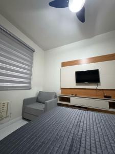 Un dormitorio con una cama y un televisor de pantalla plana. en Aconchego Constante, en Río de Janeiro