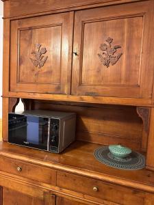a microwave sitting on top of a wooden cabinet at Il nido d'Ala in Ala di Stura