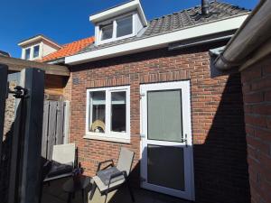 a brick house with a door and two chairs at Vlier aan zee in Katwijk aan Zee