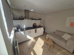 a small living room with a couch and a kitchen at Vlier aan zee in Katwijk aan Zee