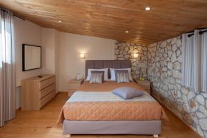 una camera con un grande letto e un muro di pietra di Anita Village a Perama