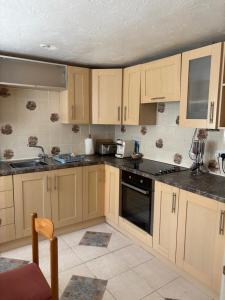 a kitchen with wooden cabinets and a stove top oven at Rosie's cottage in Woolfardisworthy