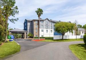 an apartment building with palm trees and a driveway at Holiday Inn Express & Suites Ormond Beach - North Daytona by IHG in Ormond Beach