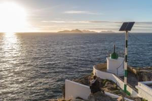 a person sitting on a rock near the ocean at Hotel Miramar Playa America Nigran in Nigrán