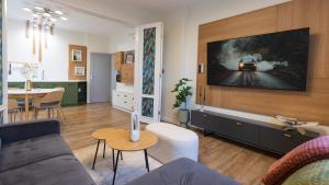 a living room with a couch and a tv on a wall at LIMIDI HOMES --- Spacious Two-Bedroom Apartment in City Centre --- Ideal Location for Exploring Veliko Tarnovo in Veliko Tŭrnovo