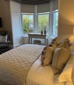 a bedroom with a large bed with windows and a desk at Crookston Hotel in Glasgow