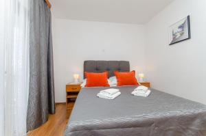 a bedroom with a bed with two orange pillows at Apartments Cosic in Igrane